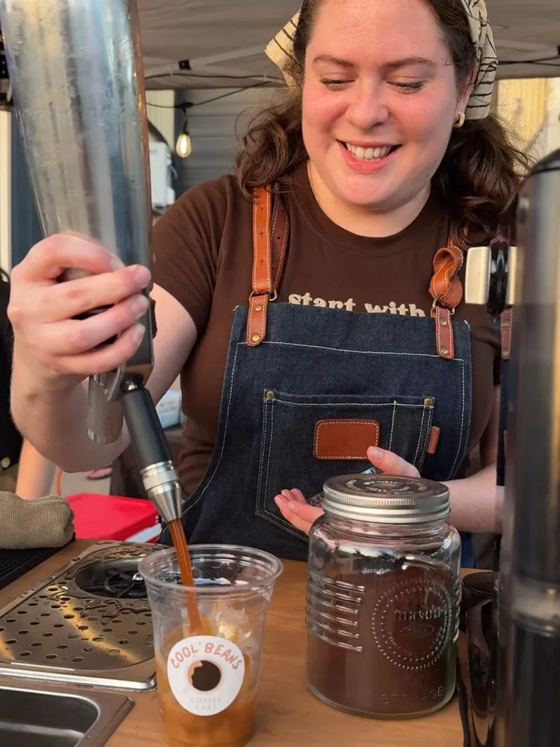 Barista pouring cold brew on tap into a Cool Beans cup